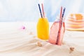 Tropical beach fruit cold strawberry and orange cocktail in wet glass bottle with straw in bright sun beam with blue ocean view. Royalty Free Stock Photo