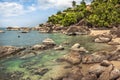 Tropical beach with hill and palm trees in lagoon with transparent turquoise water and round stones nearby tropical hotel Royalty Free Stock Photo