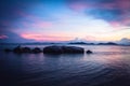 Tropical beach holidays landscape with calm turquoise sea and big round stones and rocks in sea during dramatic sunset in purple c