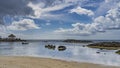 Tropical beach at low tide. Exposed rocks protrude from the water.