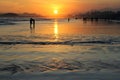 Wide open beach on the sunset with people silhouettes and orange sky. Royalty Free Stock Photo