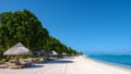 Tropical beach with palm trees and white sand blue ocean and beach beds with umbrella,Sun chairs and parasol under a Royalty Free Stock Photo