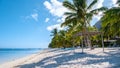 Tropical beach with palm trees and white sand blue ocean and beach beds with umbrella,Sun chairs and parasol under a Royalty Free Stock Photo