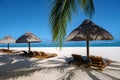 Tropical beach with palm trees and white sand blue ocean and beach beds with umbrella,Sun chairs and parasol under a Royalty Free Stock Photo