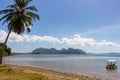 Tropical beach with palms and boat with uknown people. Beautiful lagoon in Philippines. Summer vacation. Asian travel.