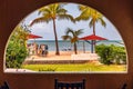 Tropical beach scene with palm trees and beach umbrellas.