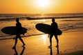 Tropical beach sea ocean with sunset or sunrise for summer travel vacation. Silhouette of surfer people carrying their Royalty Free Stock Photo