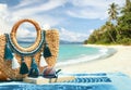 Tropical beach summer holiday accessories, with blurred beach palm trees and sea in background.