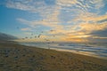 Tropical beach sunset and flock of birds, cloudy sky and sun setting down the horizon Royalty Free Stock Photo