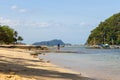 Tropical beach with trees, boats and isles on horizon. Seascape with tourist on beach. Tropic paradise.