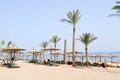 tropical beach on vacation, a tropical resort with sun beds, sun loungers and sun umbrellas in the form of straw hats on the back Royalty Free Stock Photo