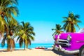 The tropical beach of Varadero in Cuba with american classic pink car, sailboats and palm trees on a summer day with turquoise Royalty Free Stock Photo