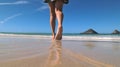 Slender female legs move away along the surf line