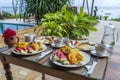 Tropical breakfast of fruit, coffee and scrambled eggs and banana pancake for two on the beach near sea. Top view, table setting Royalty Free Stock Photo