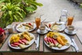 Tropical breakfast of fruit, coffee and scrambled eggs and banana pancake for two on the beach near sea. Top view, table setting Royalty Free Stock Photo