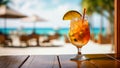 Tropical cocktail in a beautiful glass on a wooden tabletop on a blurred background of a white sand beach with some people