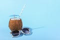 Tropical cocktail in coconut with straw and an umbrella, on paper blue and yellow background. The concept of relaxation, summer Royalty Free Stock Photo