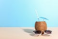 Tropical cocktail in coconut with straw and an umbrella, on paper blue and yellow background. The concept of relaxation, summer Royalty Free Stock Photo