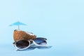 Tropical cocktail in coconut with straw and an umbrella, on paper blue and yellow background. The concept of relaxation, summer Royalty Free Stock Photo