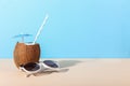 Tropical cocktail in coconut with straw and an umbrella, on paper blue and yellow background. The concept of relaxation, summer Royalty Free Stock Photo