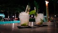 Tropical cocktails with lots of ice by a lighted pool at night