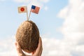 Tropical coconut with the American and Japanese flag in the form of a toothpick in female hands. Travel concept. Honeymoon Royalty Free Stock Photo