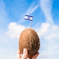 Tropical coconut with Israeli flag in the form of a toothpick in female hands. Tourist from Israel on vacation.