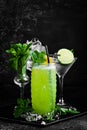Tropical delicious green alcoholic cocktail - Jungle Juice. On a black stone background. Menu bar.