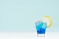 Tropical fresh alcohol cocktail with blue curacao liqueur, ice cube, sugar rim, lemon in misted shot glass on soft light white. Royalty Free Stock Photo