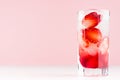 Tropical fresh strawberry cocktail with ice cubes, pieces berry on pastel pink background, copy space.
