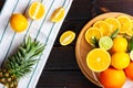 Tropical fruits on a cutting board. Pineapple, oranges, limes and lemons on a dark wooden table. View from above