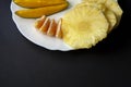 Tropical fruits, mango, pineapple and mandarin orange slices placed on white plate in half at the top, isolated on black Royalty Free Stock Photo