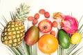 Tropical fruits, palm leaves on white background. Healthy lifestyle and summer concept. Flat lay, top view. Pineapple, lychee,