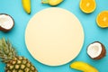 Tropical fruits. Pineapple, coconut, orange and banana on blue background. Space for text