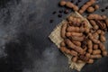 Tropical fruits, Tamarindo beans in shell on a brown butchers block on a dark background, healthy fruit. banner, menu, recipe Royalty Free Stock Photo