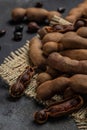 Tropical fruits, Tamarindo beans in shell on a brown butchers block on a dark background, healthy fruit. vertical image. top view Royalty Free Stock Photo