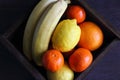 Tropical fruits in wooden basket on table top view. Juicy mandarins, orange, lemon and banana. Sweet vitamin ripe fruits. Royalty Free Stock Photo