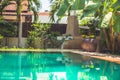 Tropical garden at modern villa with swimming pool among palm trees and Asian ornamental elements Royalty Free Stock Photo