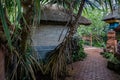 Tropical Garden Path with Traditional Huts and Exposed Tree Roots Royalty Free Stock Photo
