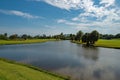 Tropical golf course with green field with trees, grass and lake.