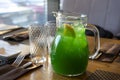Tropical green lemonade with ice in a decanter.