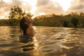 Tropical holidays lifestyle portrait of young beautiful and happy Asian Korean woman in bikini enjoying sunset at amazing jungle