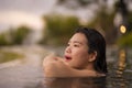 Tropical holidays lifestyle portrait of young beautiful and happy Asian Korean woman in bikini enjoying sunset at amazing jungle