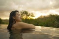 Tropical holidays lifestyle portrait of young beautiful and happy Asian Korean woman in bikini enjoying sunset at amazing jungle