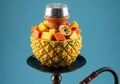 Tropical hookah with pineapple base and exotic fruits on vibrant background Royalty Free Stock Photo