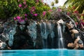 Tropical hotel pool waterfall + bougainvillea