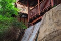 Tropical house standing on a hill with a waterfall. Trees in the background.