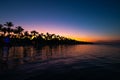 Tropical island at night. Palm trees silhouettes and lights on resort beach Royalty Free Stock Photo