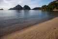 Tropical island sand beach and seaside landscape. Sea view with distant mountain. Sunset seascape with tourists Royalty Free Stock Photo