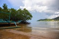 Tropical island seashore. Mangrove forest landscape. Old fisherman boat abandoned on beach